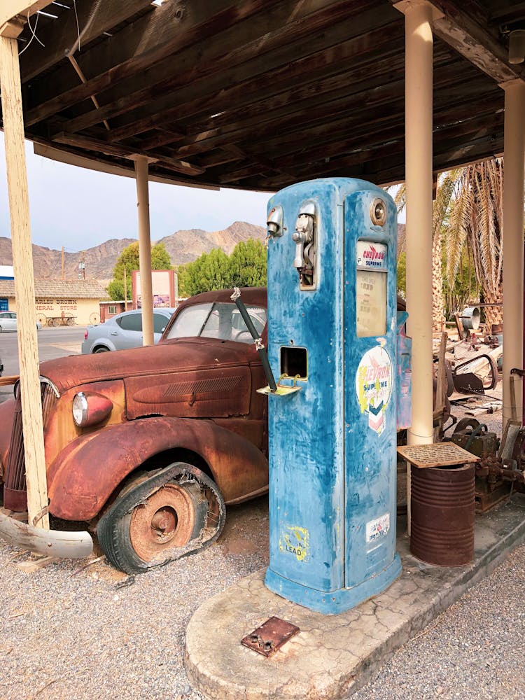 Broken Rusty Car And A Vintage Gas Pump