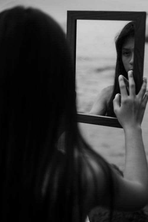 Grayscale Photo of Woman Holding a Mirror