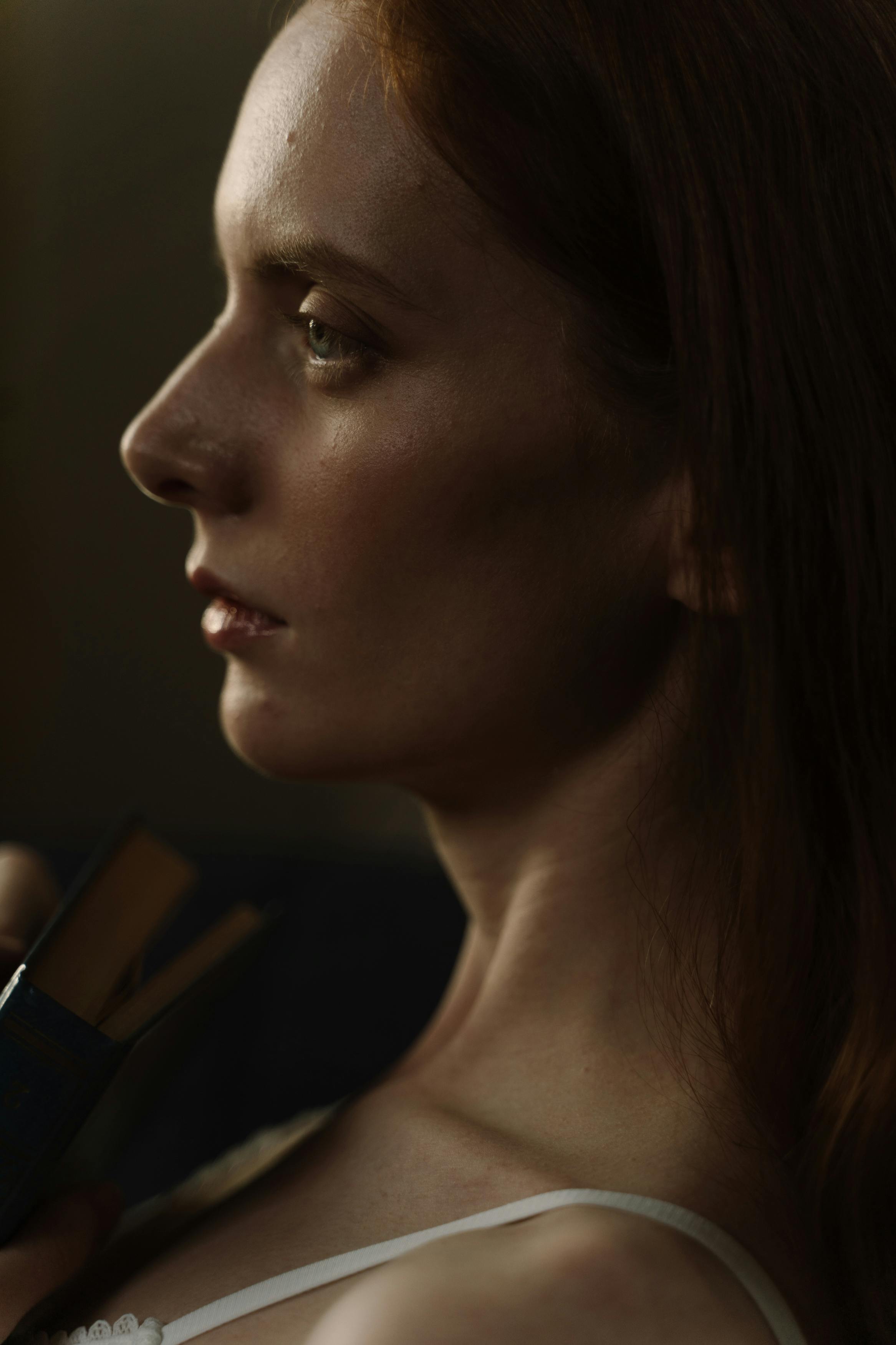 Moody portrait of a woman gazing thoughtfully, captured in profile view.