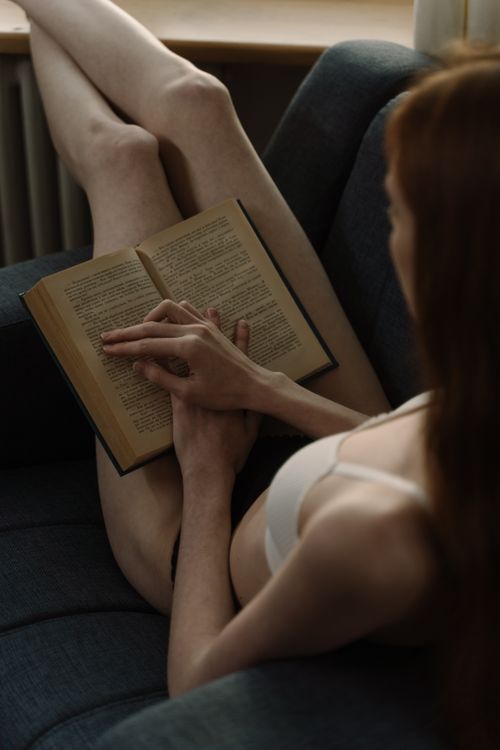 Free A woman in casual wear reading a book at home, creating a relaxed and cozy atmosphere. Stock Photo