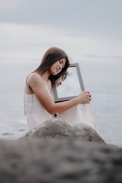 A Beautiful Woman in a White Dress Posing with a Mirror