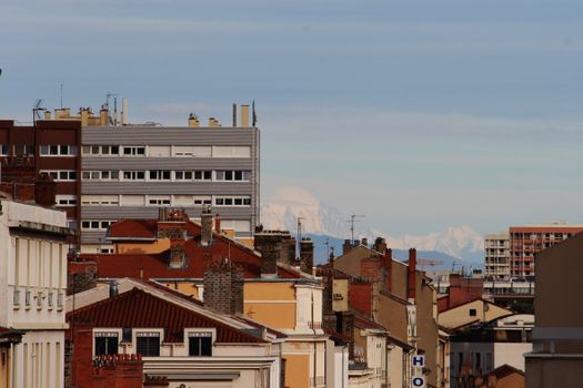 Vibrant cityscape showcasing urban architecture with distant mountains under a clear sky.