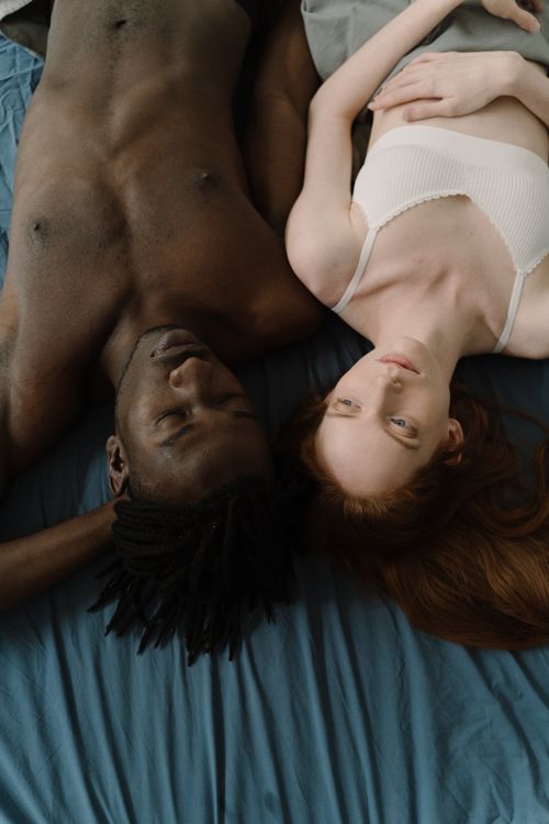 Free A serene moment of an interracial couple lying side by side, intimate and peaceful. Stock Photo