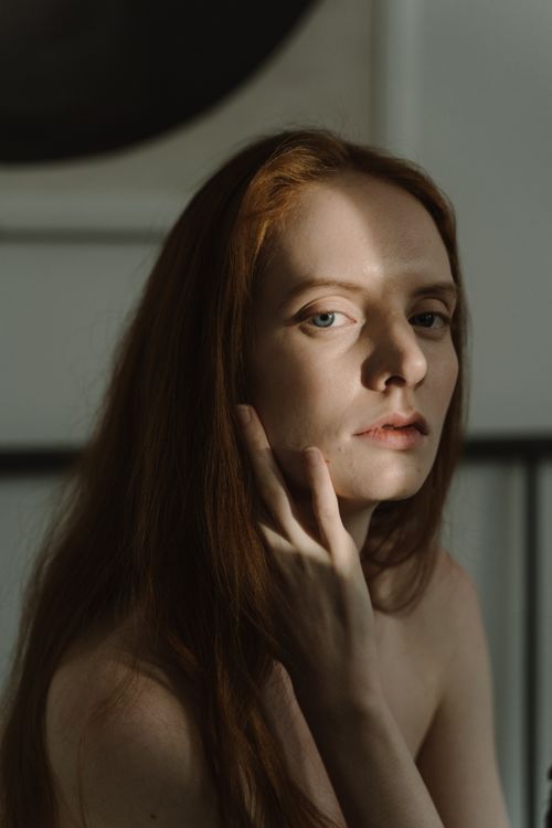 Free A redheaded woman in soft shadows poses thoughtfully, highlighting a classic beauty in natural light. Stock Photo