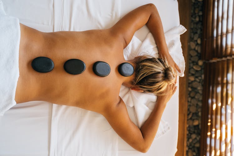 Top View Of A Person With Hot Stones On Their Back