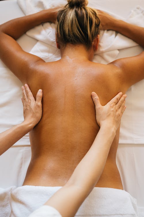 A Woman Lying Down while Getting a Body Massage