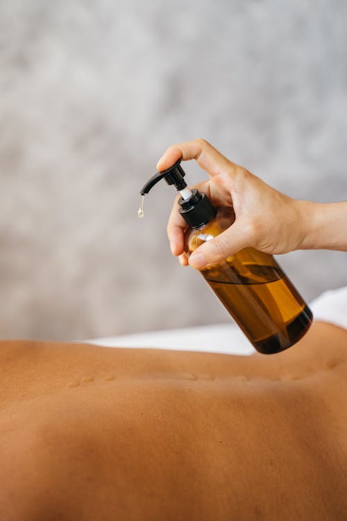 A Person Holding a Pump Bottle with Massage Oil