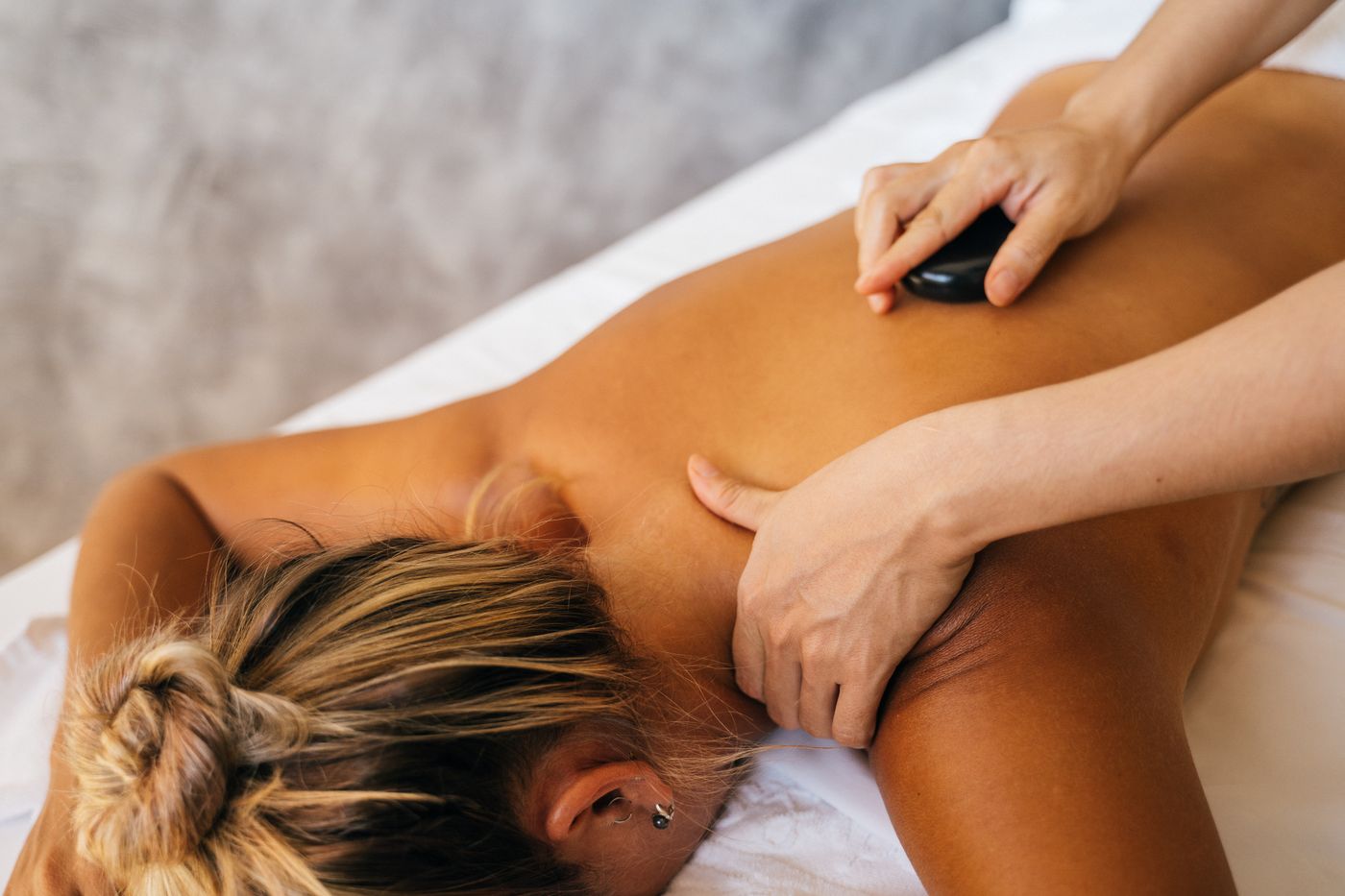 Therapist using a warm stone during a professional spa massage treatment