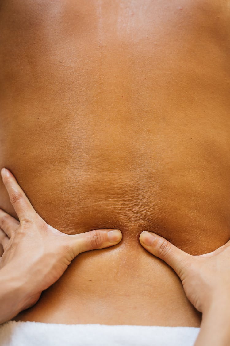 A Massage Therapist Massaging A Client's Bare Back