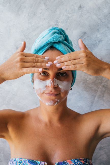 A woman applies facial cream for a moisturizing skincare routine, featuring a focus on beauty and self-care.