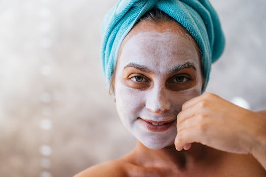 Woman with a facial mask and towel smiling, perfect for skincare and wellness themes.
