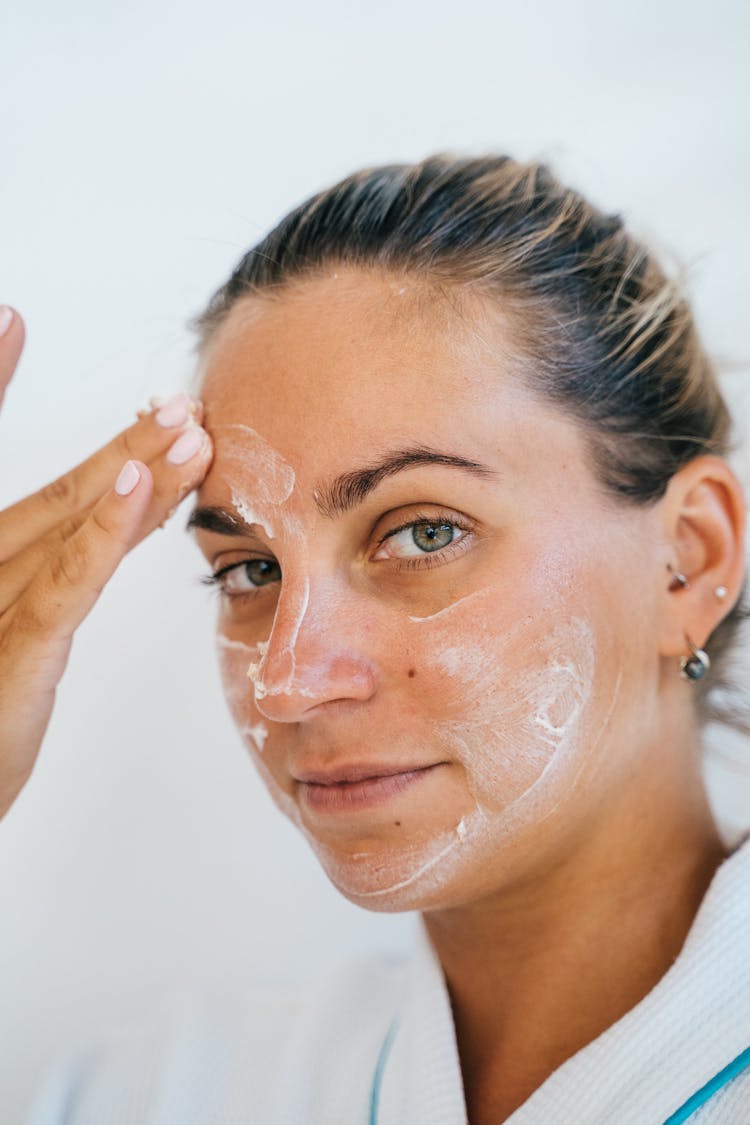 A Beautiful Woman Applying Moisturizer On Face