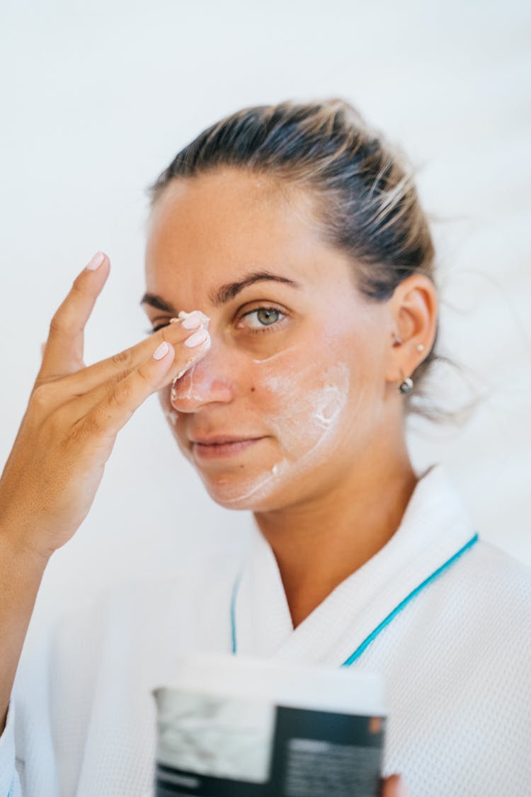 Woman Applying Cream On Her Face