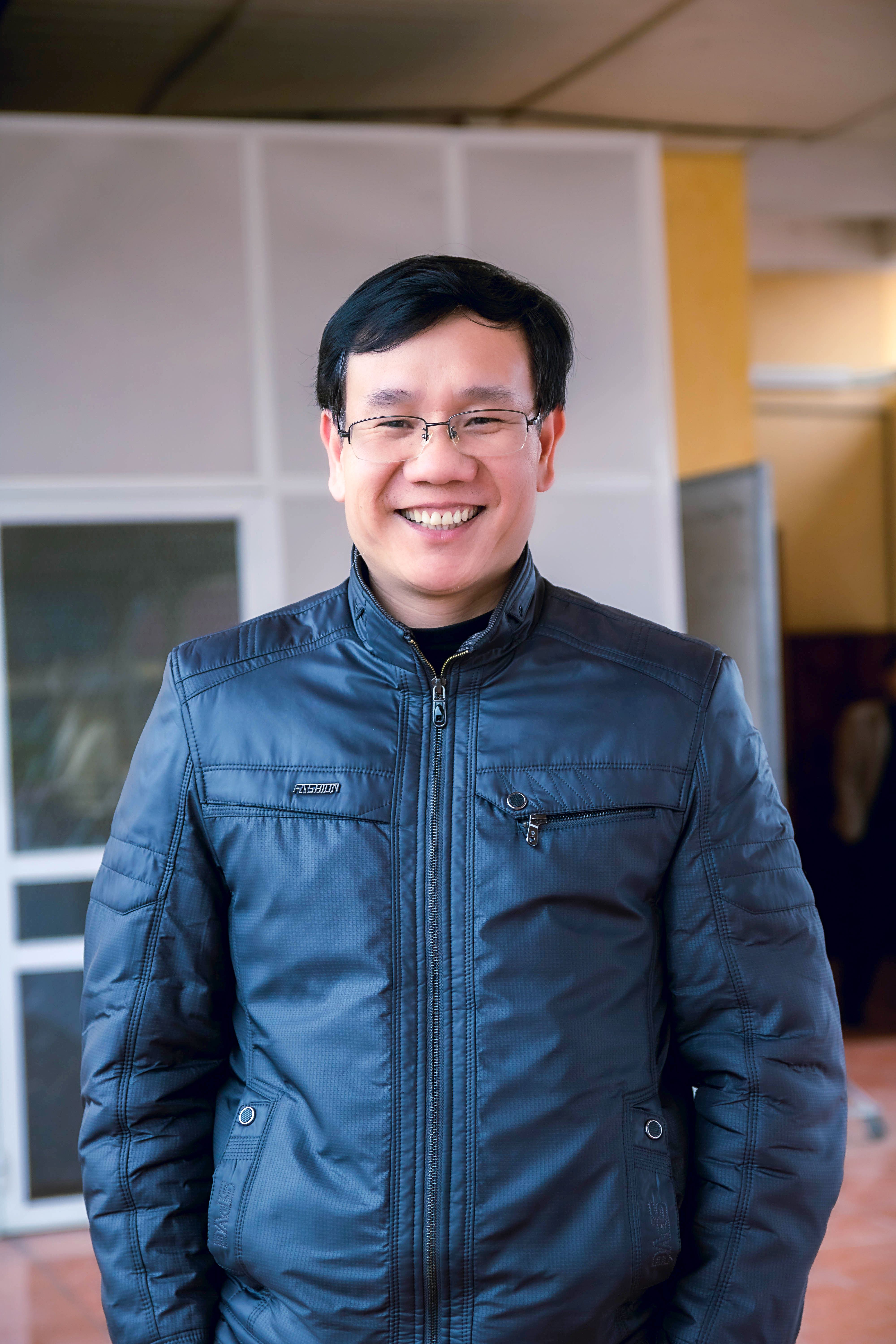 Portrait of a smiling man in a black leather jacket, indoors.