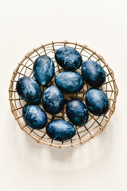 Free A stylish top-down view of blue painted Easter eggs in a wire basket on a white background, ideal for holiday themes. Stock Photo