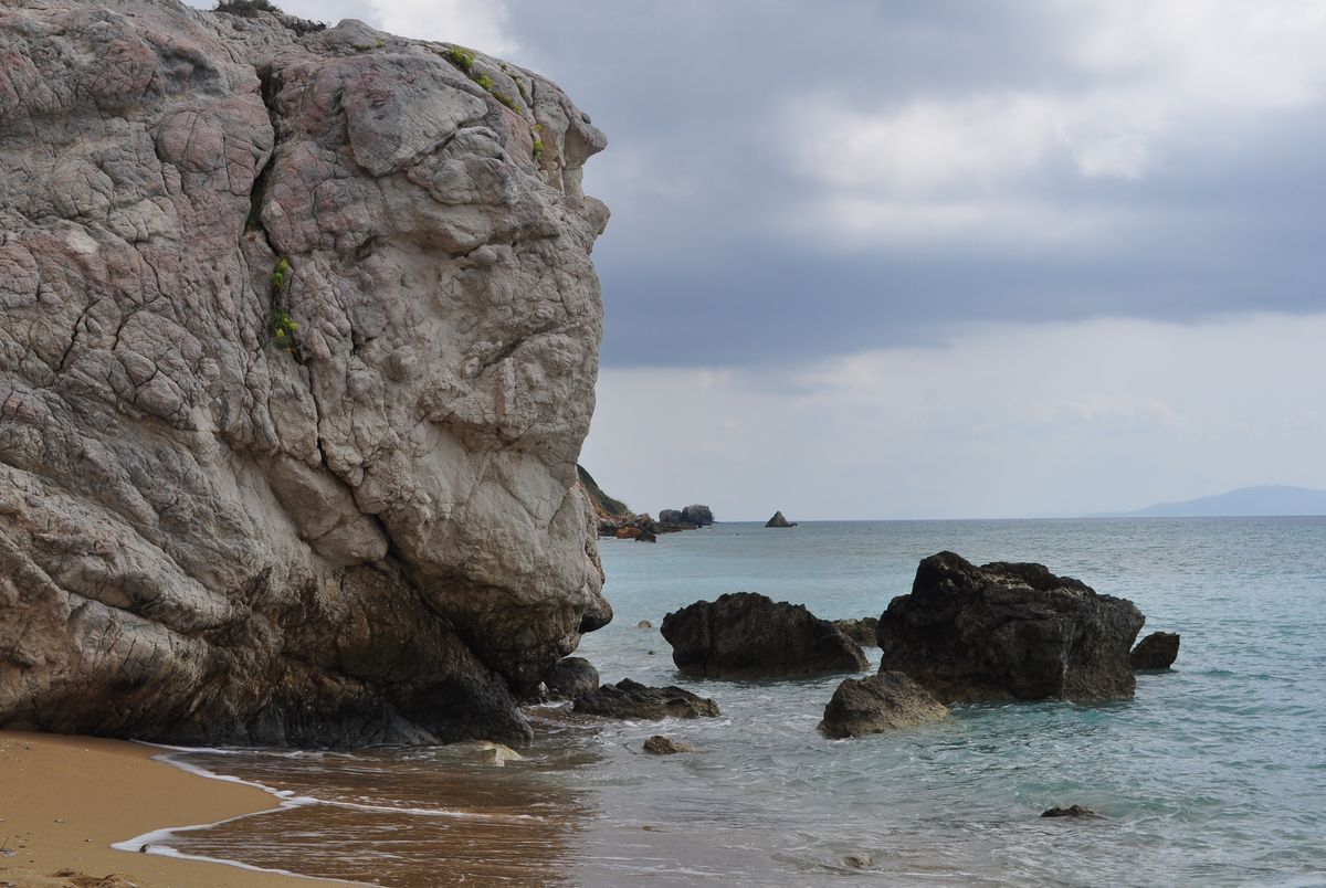 Kefalonia - coastă stâncoasă cu cer înnorat și valuri, aproape de o plajă din nord