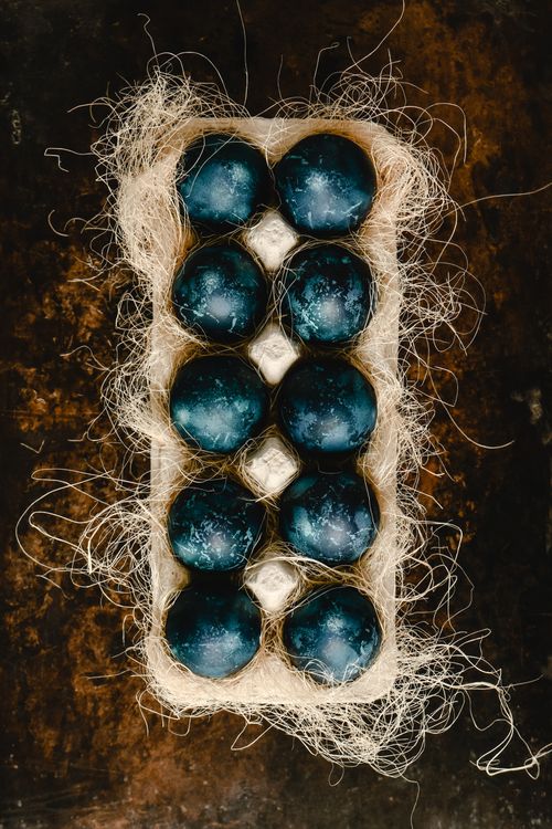 Free Top view of a nest-like egg tray with artistic painted blue eggs in a rustic setting. Stock Photo