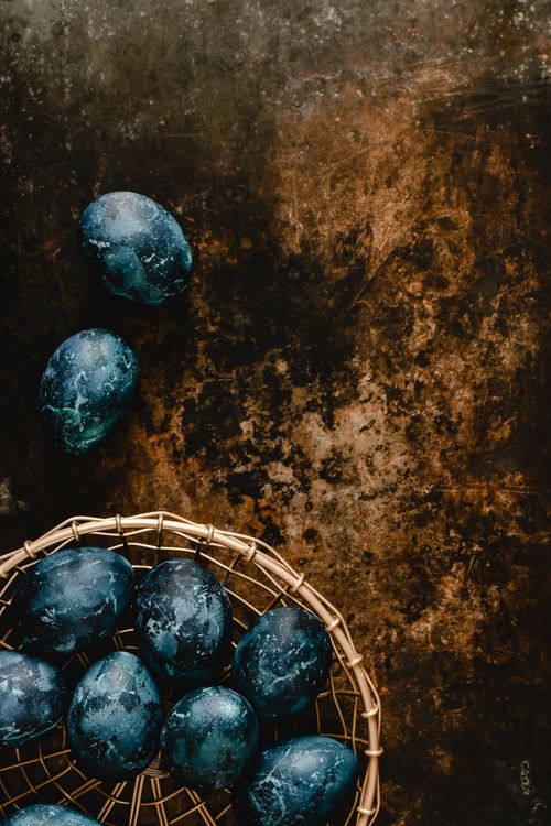 Free A top-down view of intricately painted blue marble Easter eggs in a basket on a rustic surface. Stock Photo