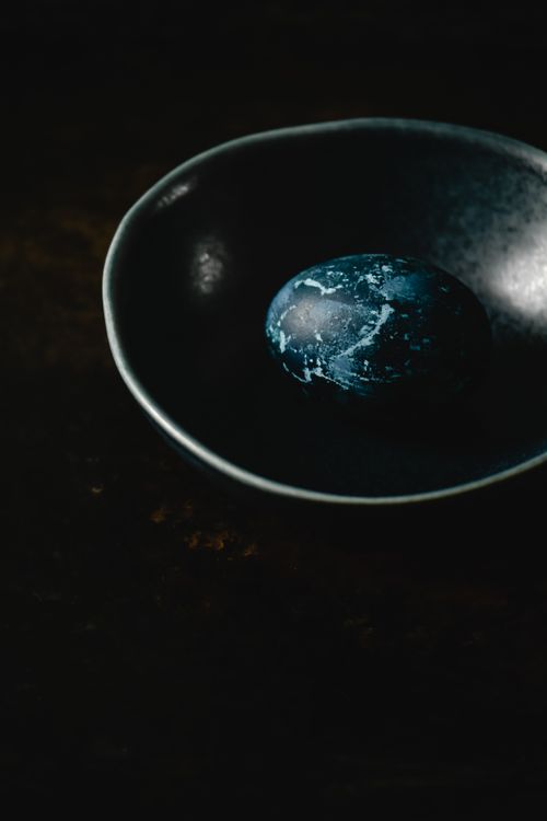 Free Artistic moody still life featuring a blue egg inside a dark bowl, creating a dramatic contrast. Stock Photo