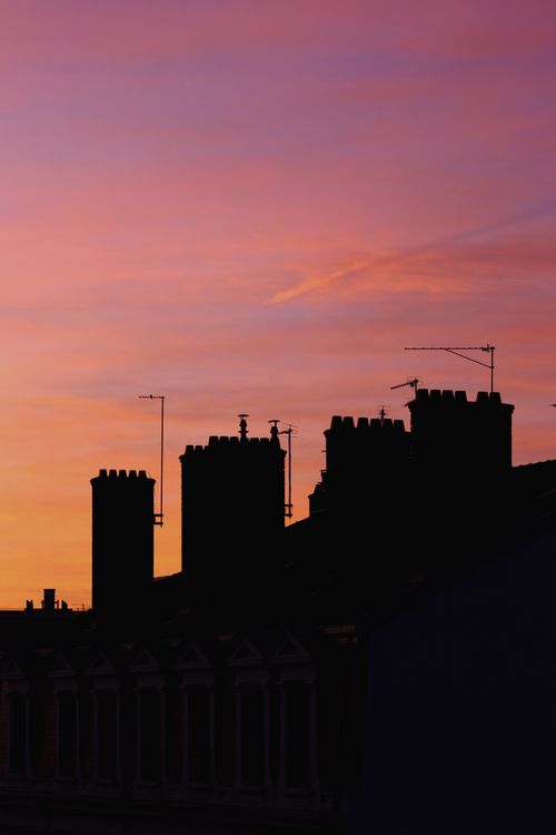 Free Silhouette of rooftops with antennas during a dramatic sunset, creating an urban skyline. Stock Photo