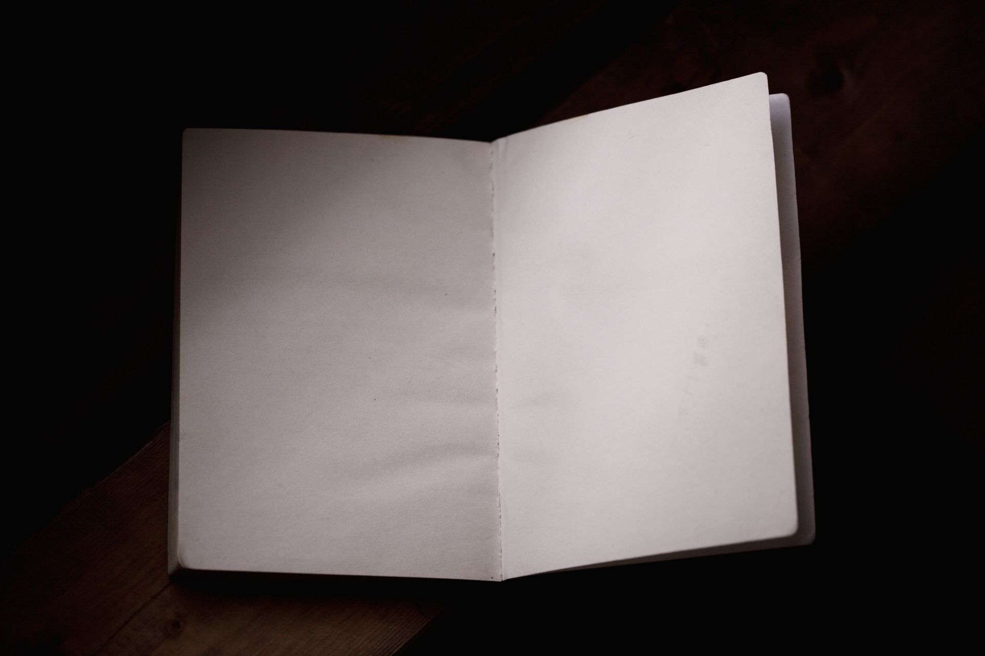 A minimalist scene with an open notebook on a wooden table, ideal for workspace themes.