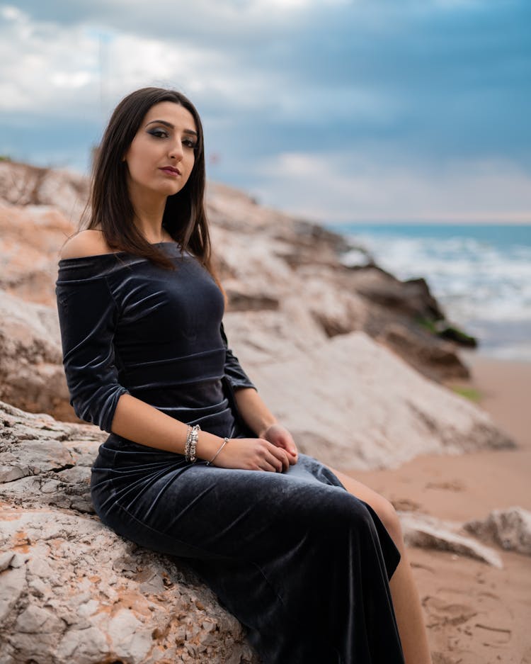 A Woman Wearing A Velvet Dress Sitting On A Rock