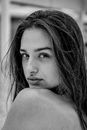 Black and white side view of young tender woman looking at camera over shoulder on blurred background