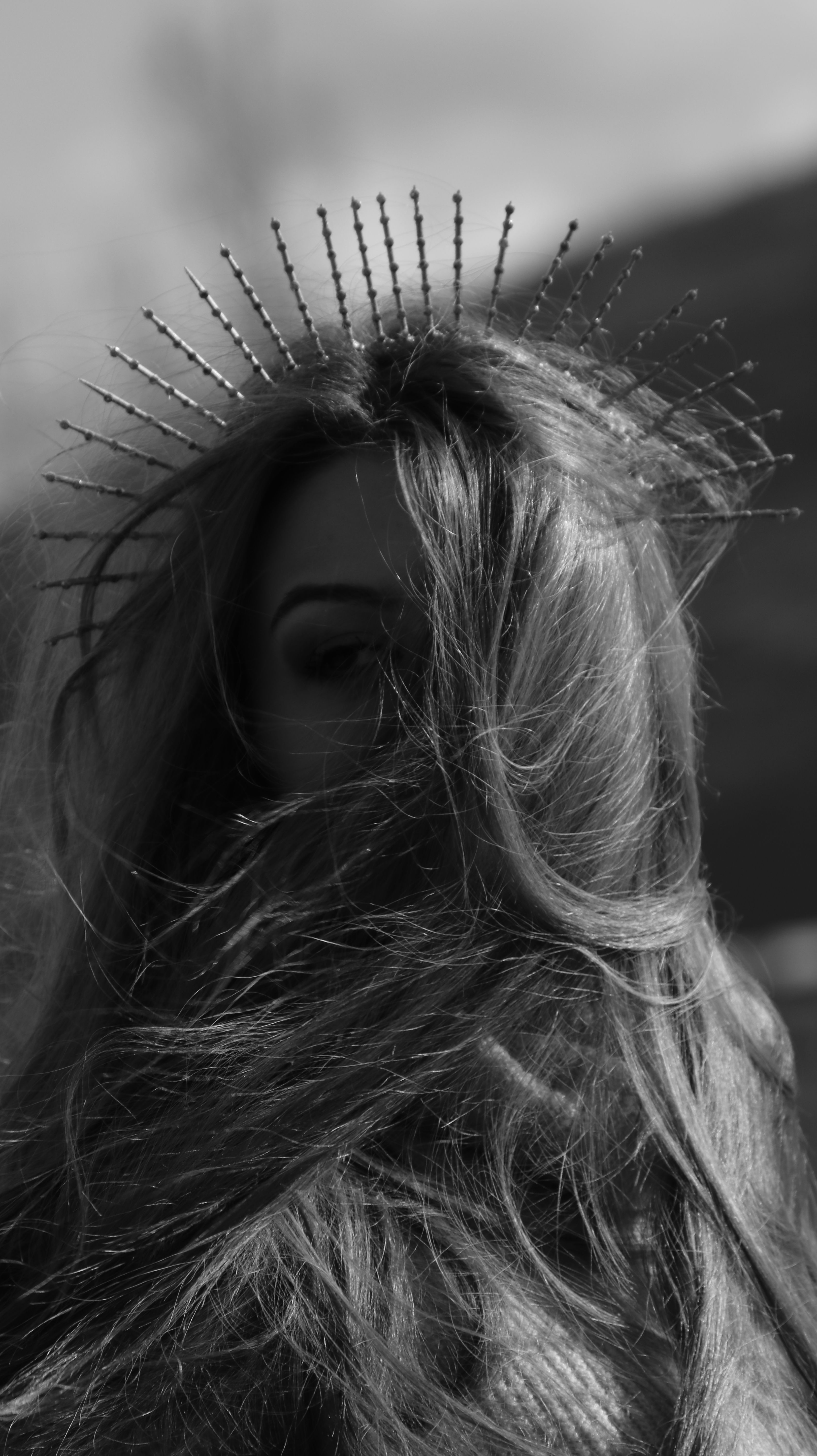 Dramatic black and white portrait of a woman wearing a unique headpiece, with emphasis on flowing hair.