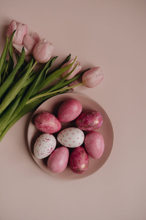 Colorful Easter Eggs on a Plate beside the Blooming Tulips