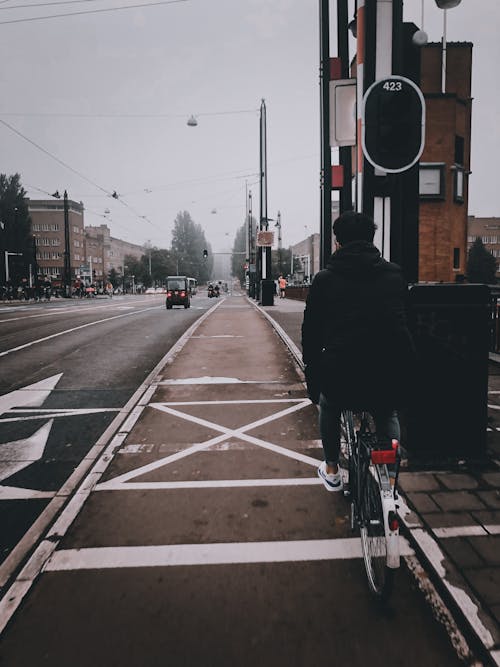 A Person in Black Jacket Riding a Bicycle on the Street