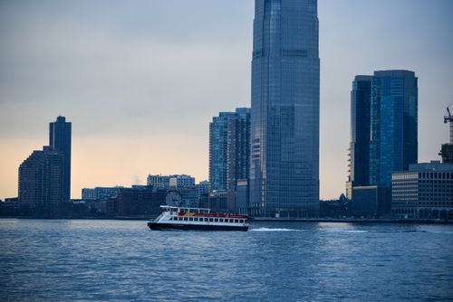Free A ferry sails across the Hudson River against New York City's skyscrapers at dusk. Stock Photo