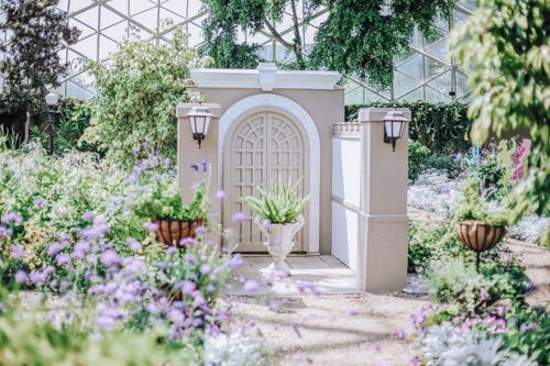 Free A tranquil garden scene featuring a beautiful arched entrance surrounded by blooming flowers and lush greenery. Stock Photo