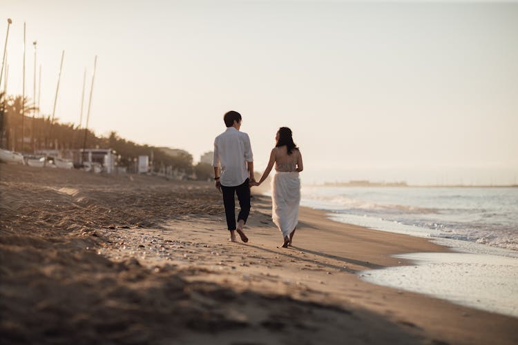 Back View Of A Couple Walking On The Beach