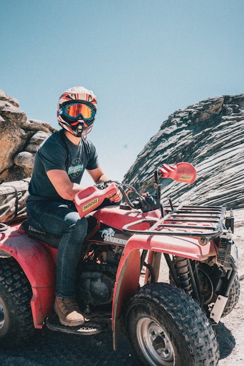 Man Riding on a Red Quad Bike Wearing a Helmet