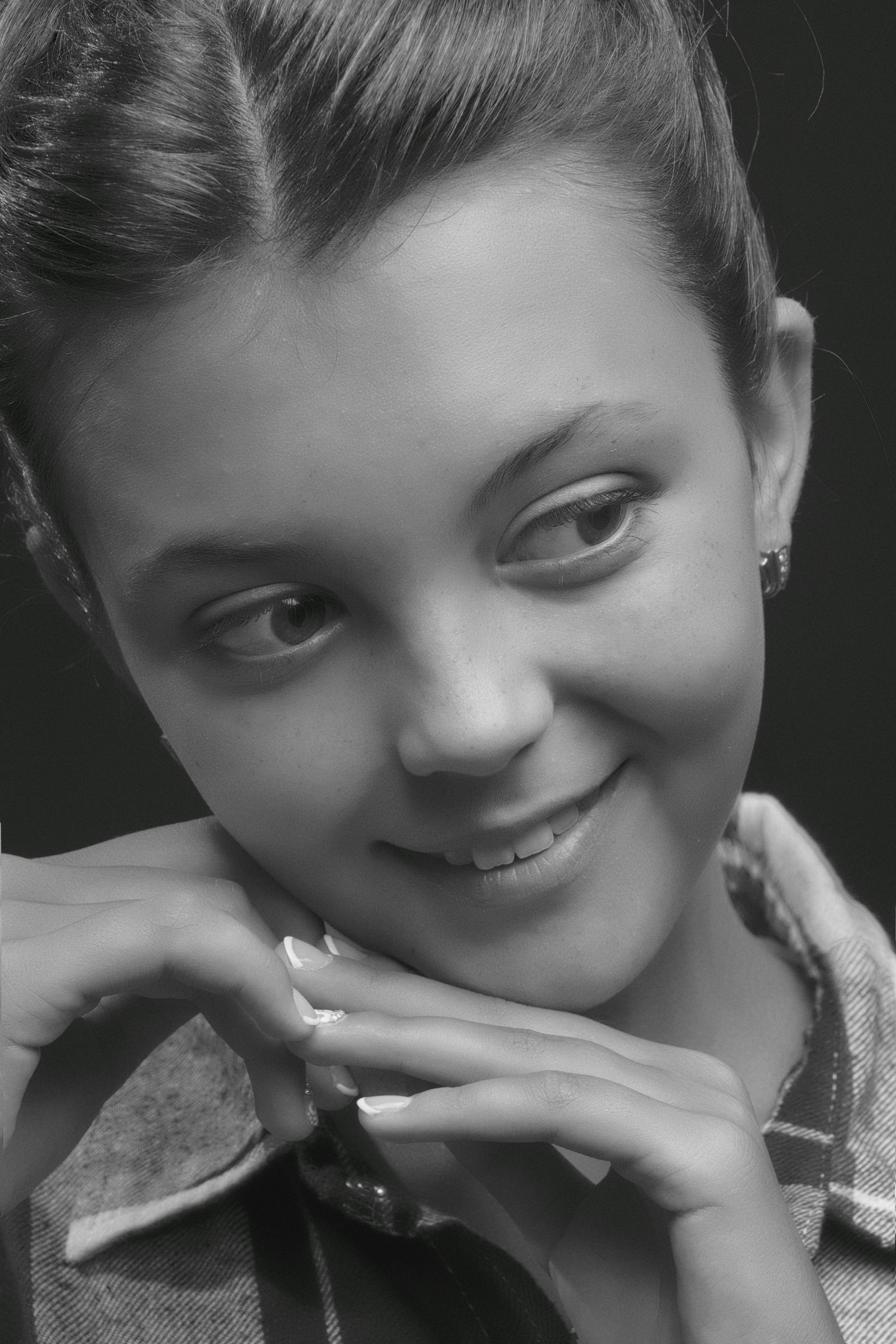 Close-up grayscale portrait of a smiling young woman with a relaxed pose.