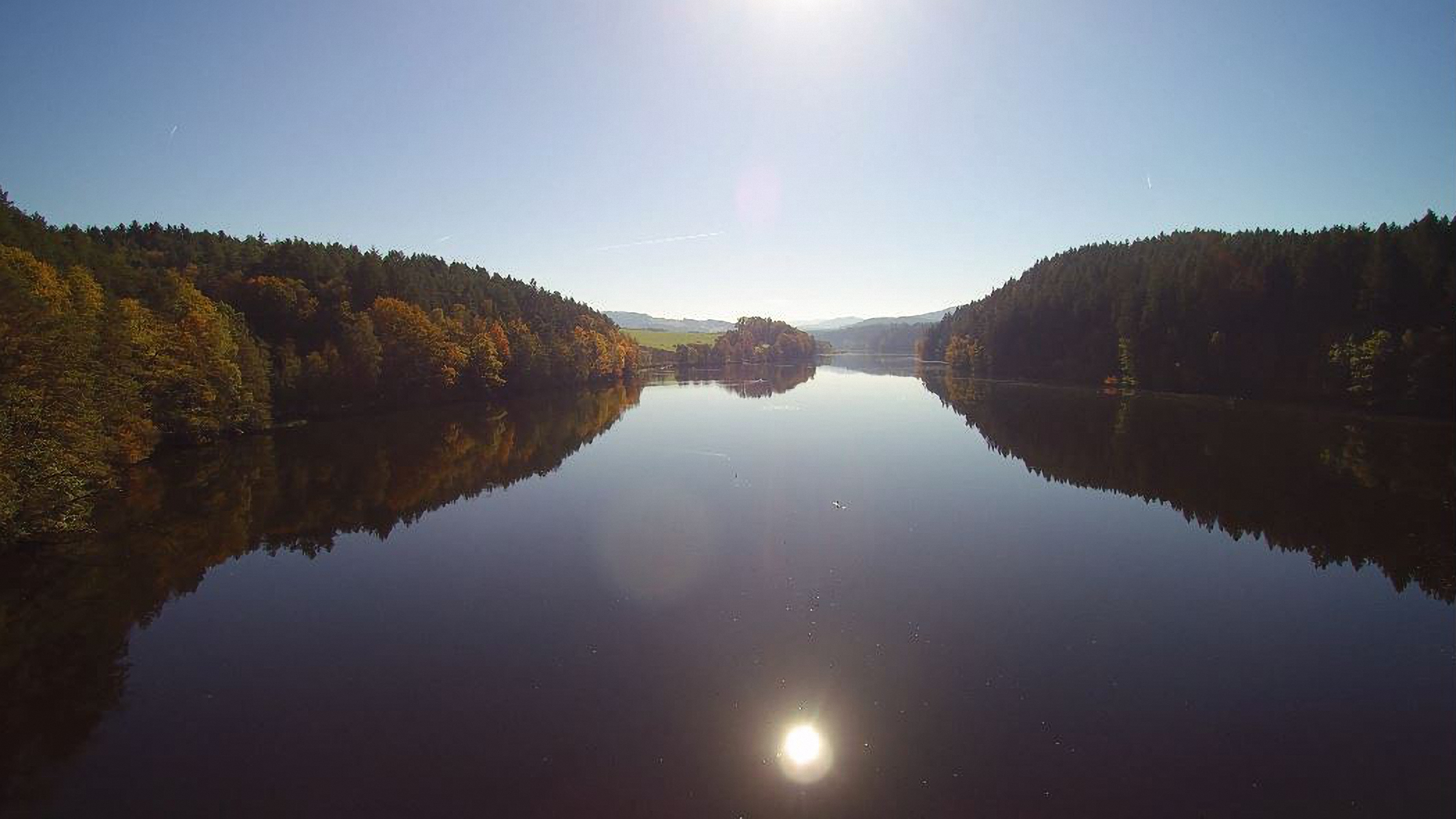 Serene lake scene with clear water reflecting trees and sky in Vinh Phuc, Vietnam.