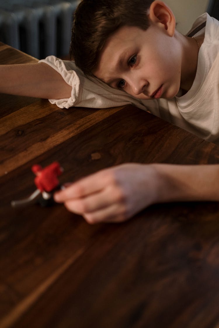 A Sad Child Playing Alone With A Hockey Player Toy