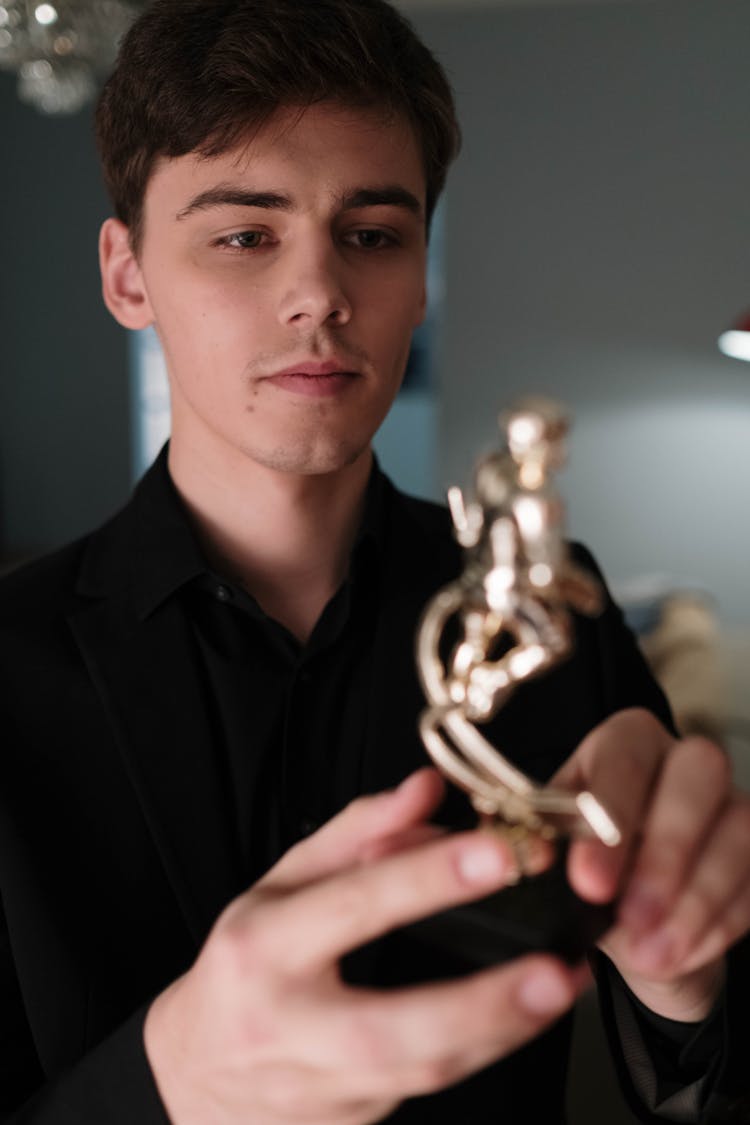 Man In Black Long Sleeves Holding A Gold Trophy 