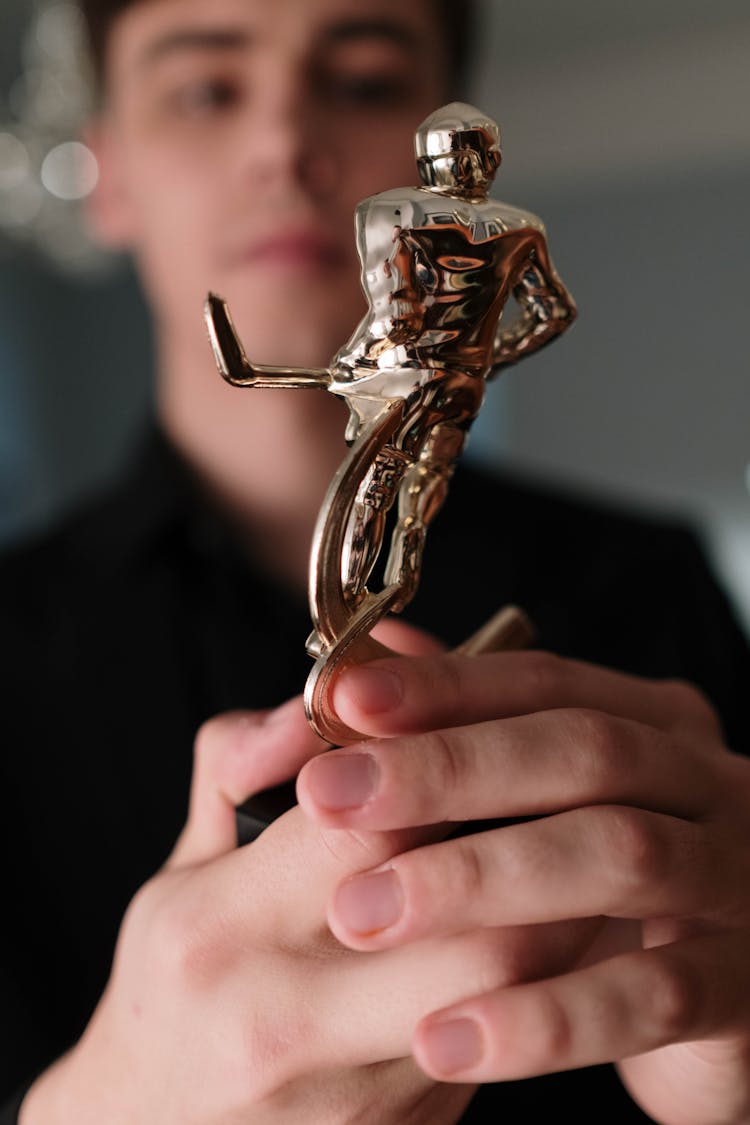 Person Holding A Gold Trophy 