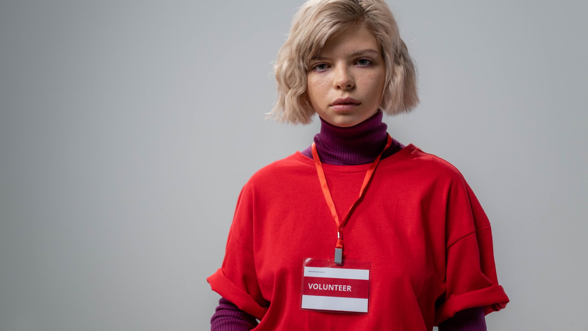 ID Cards: Your Essential Identification Companion 7 Portrait of a young female volunteer wearing a red shirt and name badge against a neutral background — id cards