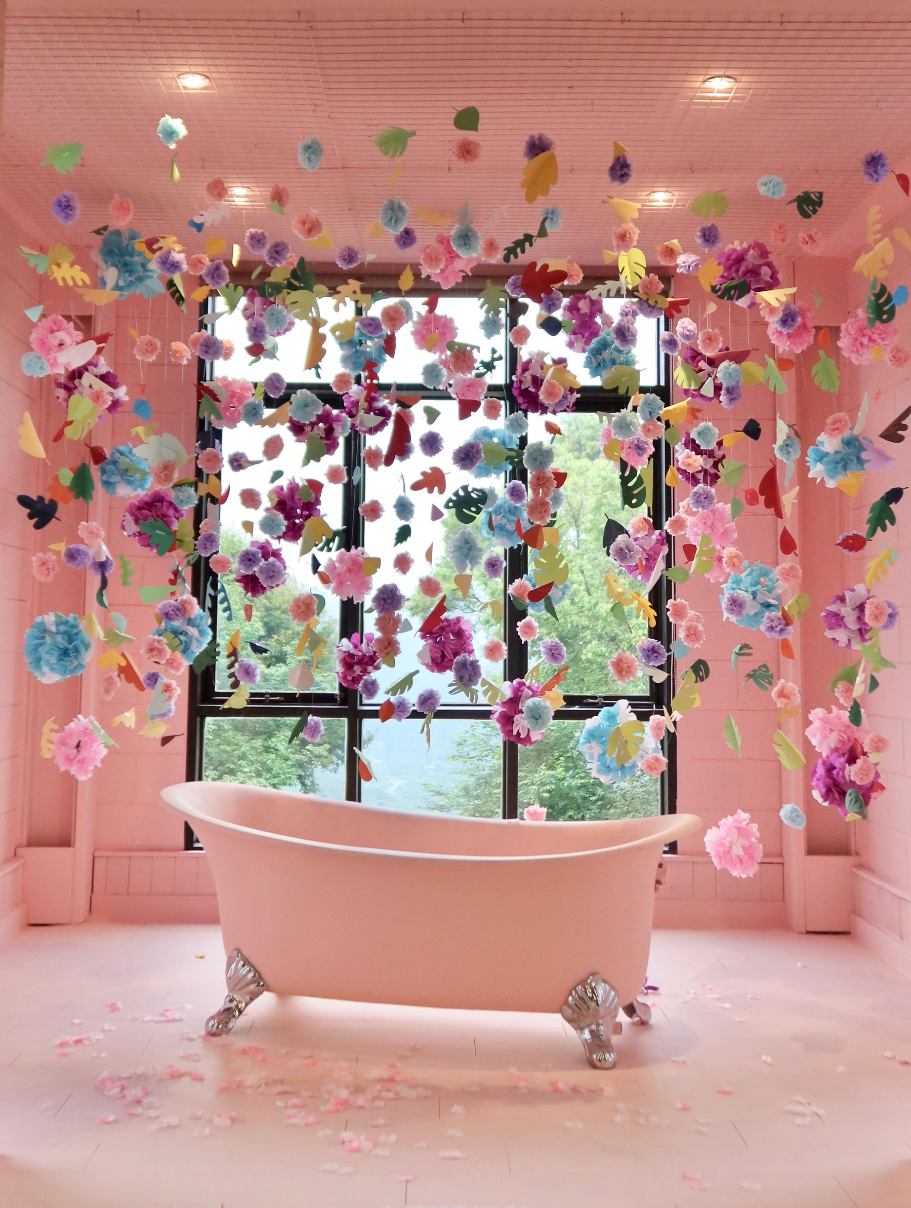 Playful pink bathroom with classic bathtub, pale walls and floral accents