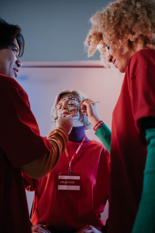 Free A group of volunteers face painting indoors, promoting creativity and teamwork. Stock Photo