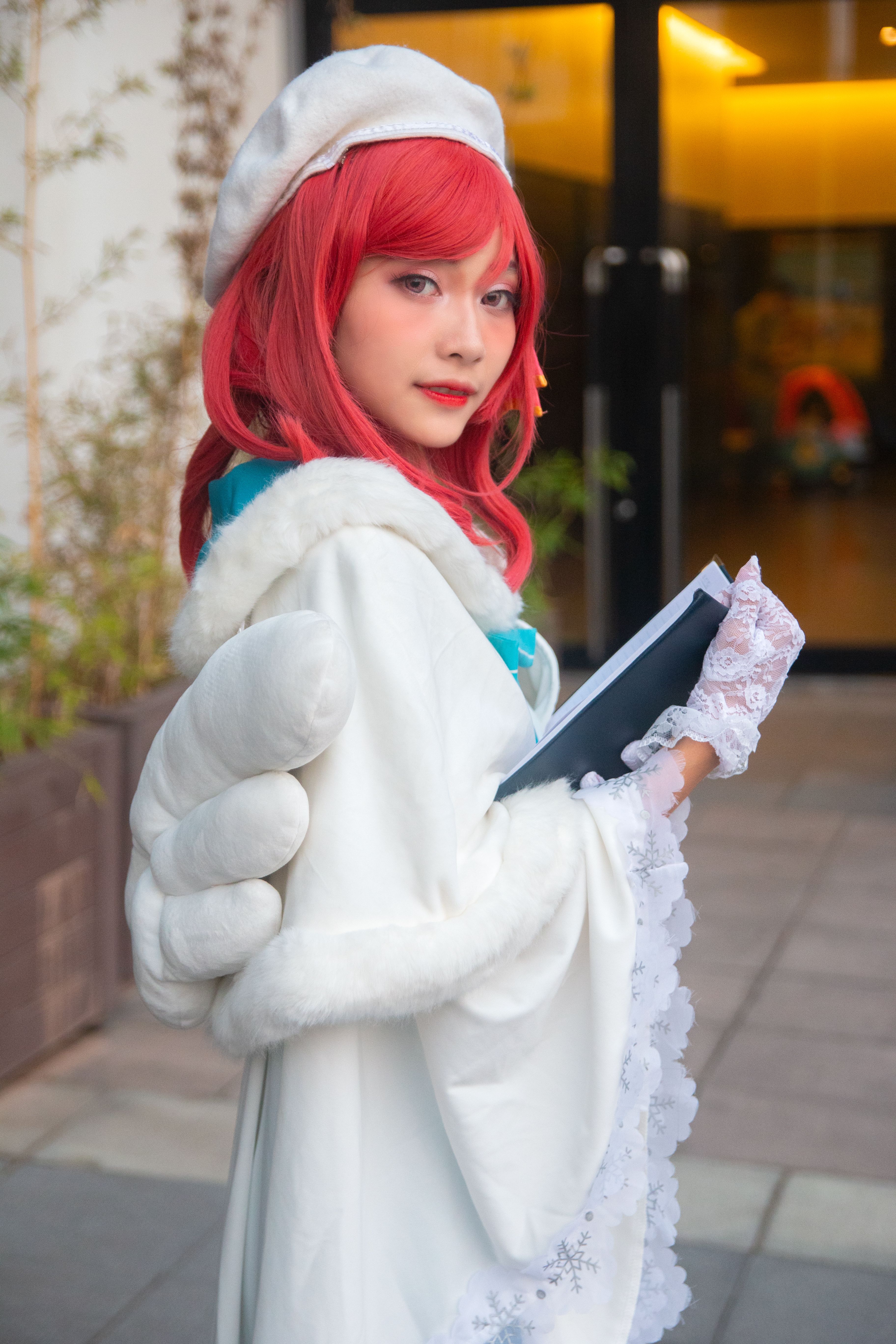 Cosplayer dressed as anime character in elegant white costume outdoors.