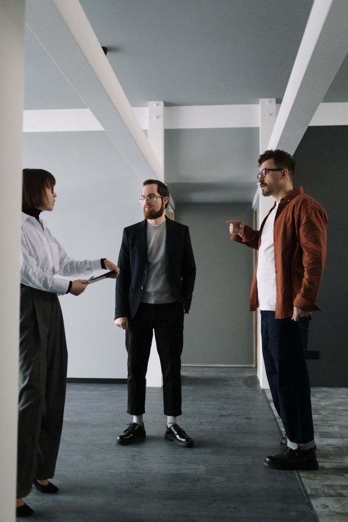 A broker showing two clients an empty office floor.