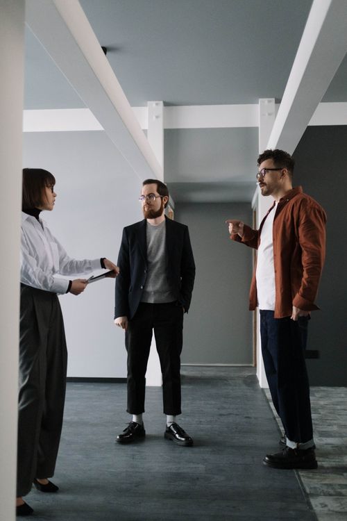 Free Three professionals engaged in conversation in a modern office corridor. Stock Photo