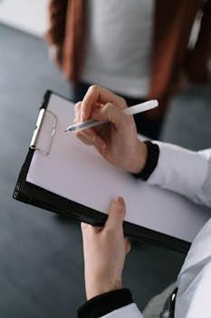 A detailed close-up of a professional holding a clipboard and pen, capturing a moment of concentration.