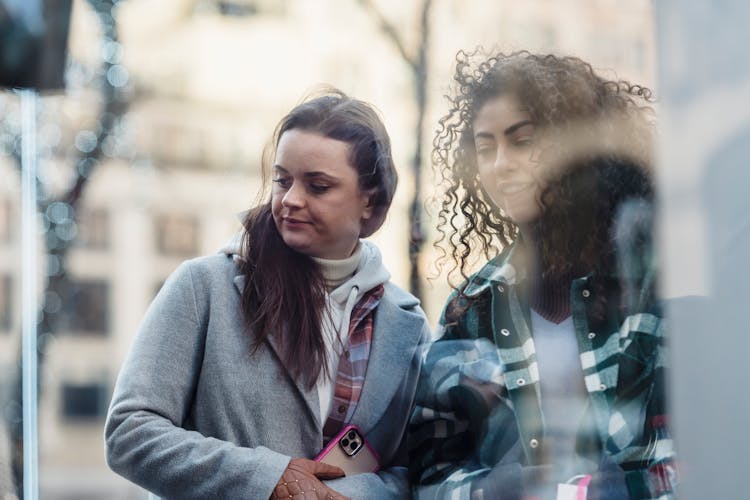 Through Glass Of Content Multiethnic Women Near Shop Window