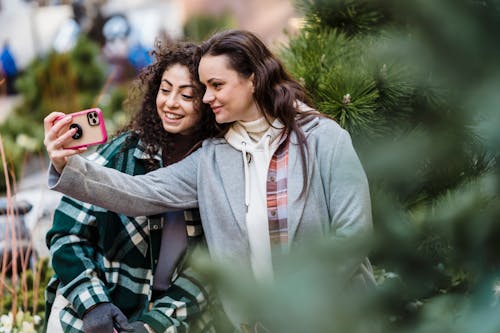 Cheerful friends taking selfie on smartphone on street