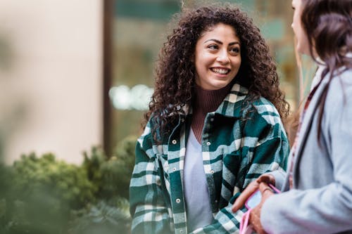 Smiling female communicating with friend against building