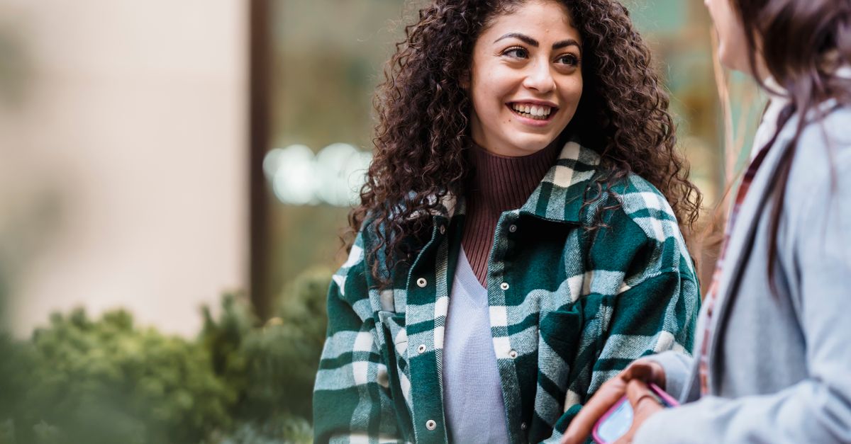 A young person laughing and talking with friends outside a church building, natural lighting, casual clothes